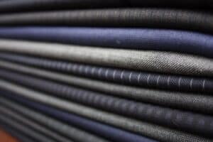 Luxurious men's fabric swatches showcasing high-quality tailored fabrics for bespoke Sartoria Bespoke suits.